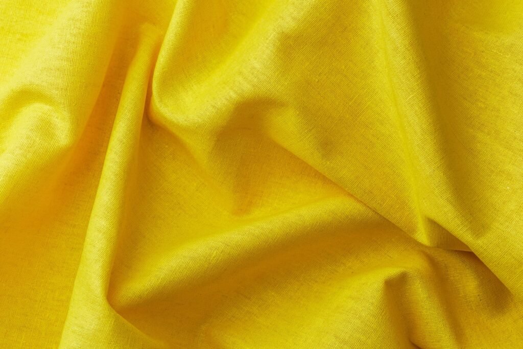 Yellow fabric with soft wrinkles and folds close up background